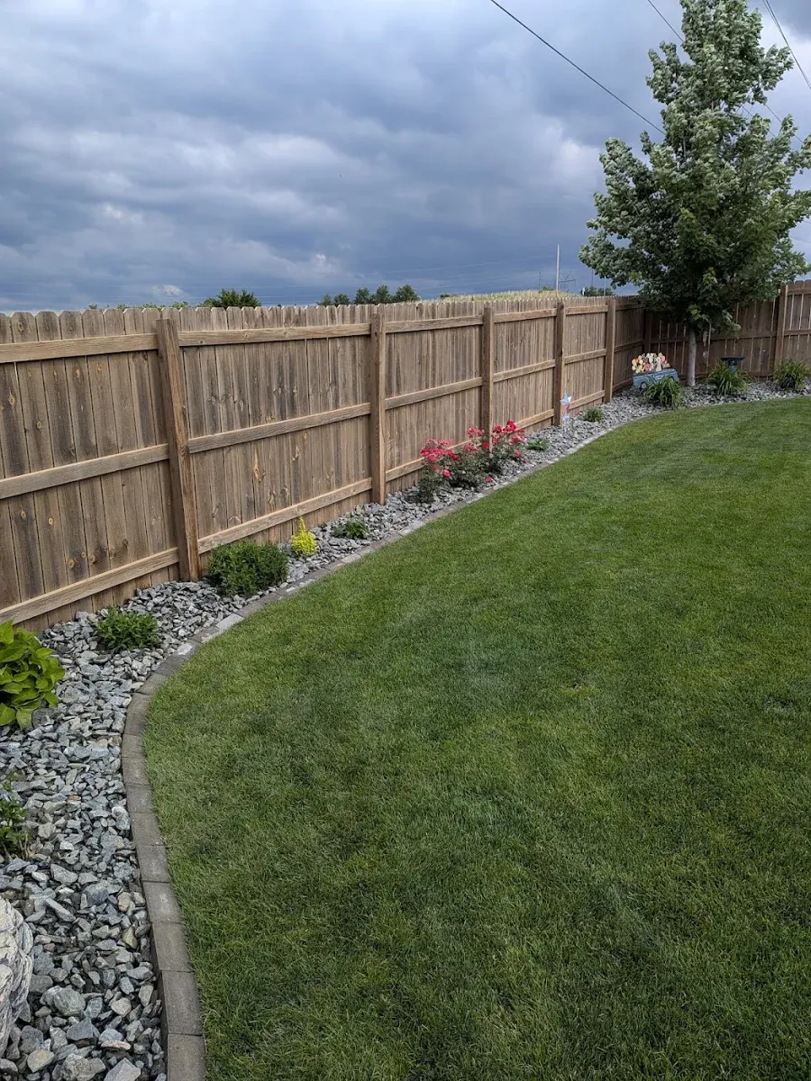 Maintained lawn and curved landscape bed beside a fence in the Omaha area
